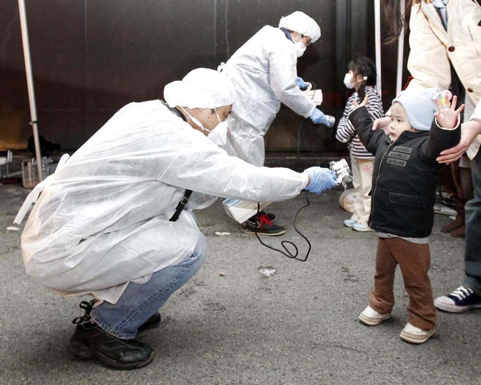 File photo of officials in protective gear checking for signs of radiation on children who are from the evacuation area near the Fukushima Daini nuclear plant in Koriyama