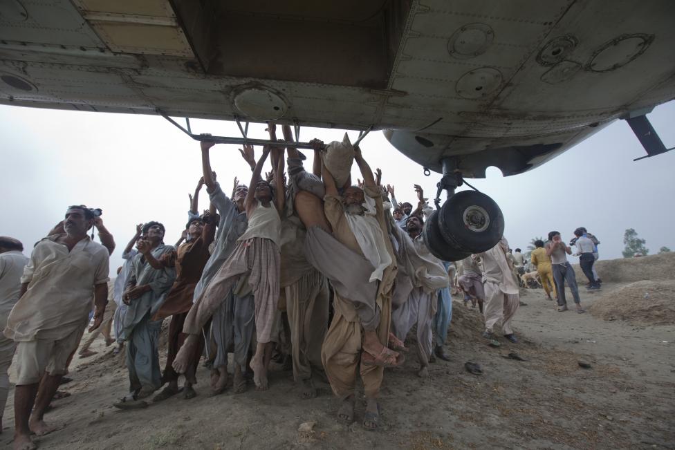 File photo of Marooned flood victims trying to grab the side bars of a hovering Army helicopter which arrived to distribute food supplies in the Muzaffargarh district of Pakistan's Punjab province