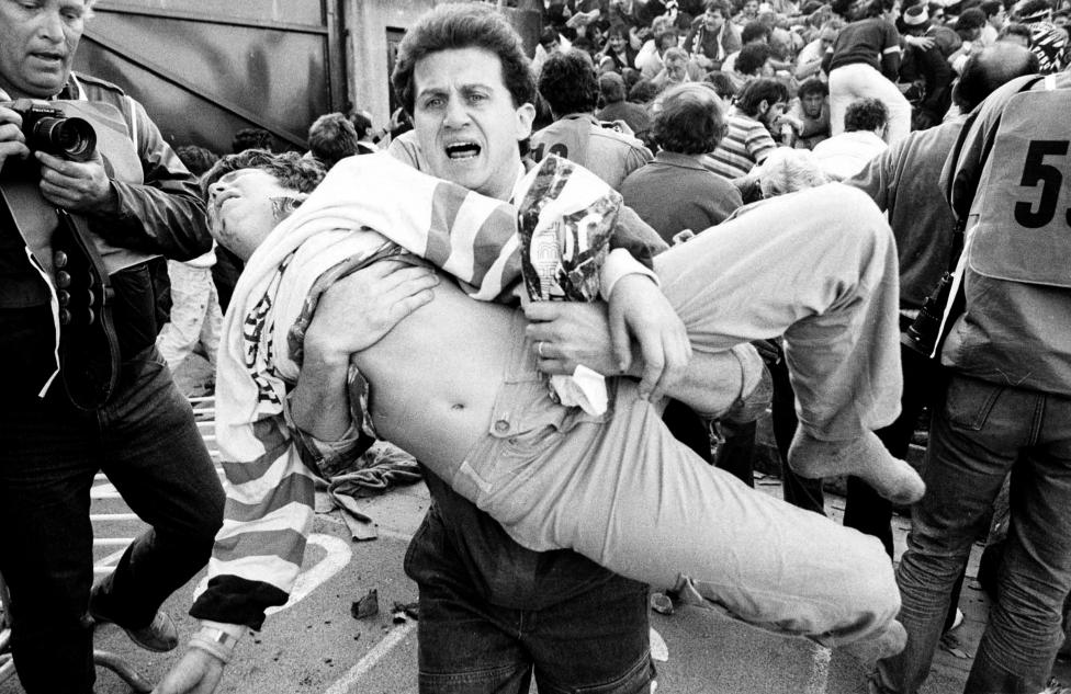 File photo of an injured soccer fan being carried to safety by a friend after a wall collapsed during violent rioting before the European Cup final between Juventus and Liverpool