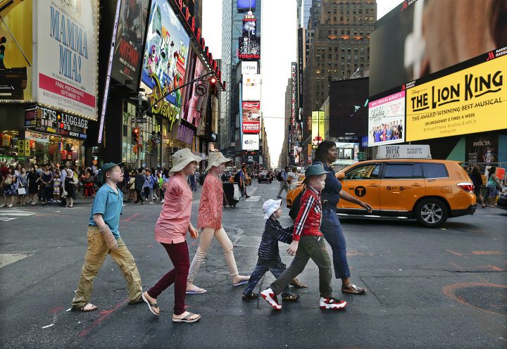 From left, Emmanuel Rutema, Kabula Masanja, Pendo Noni, Baraka Lusambo and Mwigulu Magesa walk through Times Square with Monica Watson, right, in New York on Tuesday, July 28, 2015. The children were attacked and dismembered in Tanzania because of a belief that her body parts will bring wealth. (AP Photo/Julie Jacobson)
