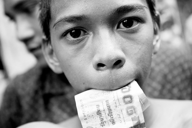 A boy with money in his mouth. After winning the boxing match wi