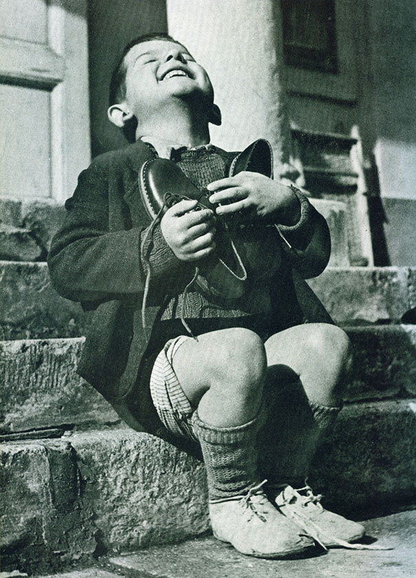photos rares 20eme siecle Un petit garcon recoit une paire de souliers neufs pendant la deuxieme guerre mondiale