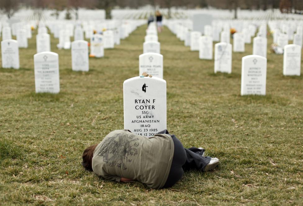 File photo of a woman lying down in front of the grave of her brother at Arlington National Cemetery near Washington