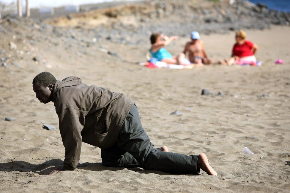 File photo of a would-be immigrant crawling on a beach after his arrival in Fuerteventura
