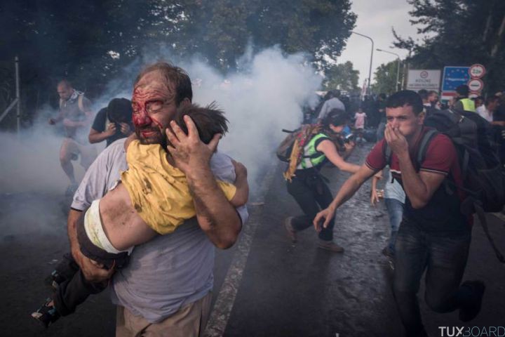 A migrant holds his child during a clash with Hungarian riot police at the Horgos border crossing in Serbia, Sept. 16, 2015. Hundreds of migrants remained stranded on Serbia?s border with Hungary early Wednesday as Hungary?s decision to seal its border rippled across Europe and other migrants scrambled to find alternative routes, in an effort, in most cases, to reach Germany. (Sergey Ponomarev/The New York Times)