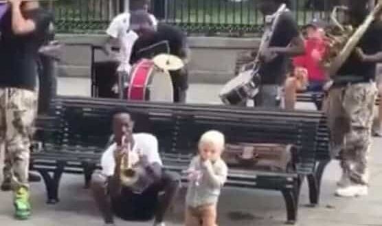 Ce petit garçon joue de la musique avec un orchestre de rue